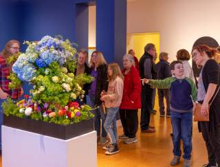 A group of people looking at a flower display in an art museum