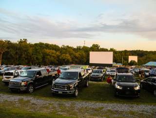 Cars parked in front of a field with a large projector