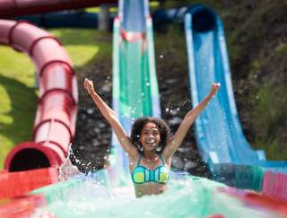 A young girl exits water slide with splashing water