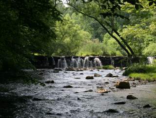 A waterfall flowing into a stream with rocks in a state park