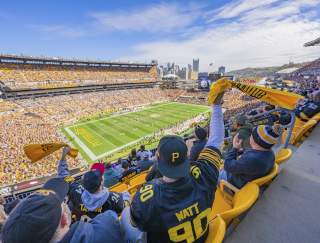 People in the stands of a football stadium waving yellow towels
