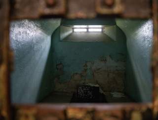 An old, eerie jail cell with a glowing window at the top