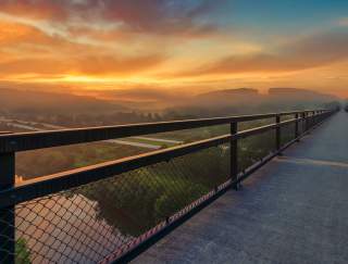 An overlook of a sunset with a metal railing
