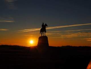 A statue of a man on a horse at sunset