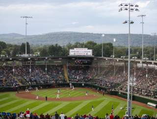A baseball stadium filled with people watching a baseball game. A sign on the top of the stadium reads Welcome to Howard J. Lamade Stadium