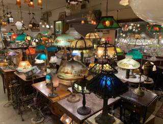 Interior of an antique store with a lot of lamps on various tables