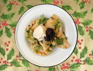 A plate of pierogies with garnish set on a decorative table cloth with holly