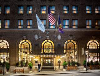 Exterior of a historic hotel with three flags hanging in front of the entrance