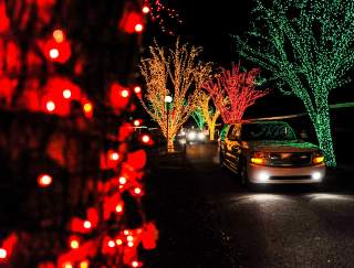 A car driving through a Christmas light display at night