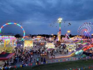 Aerial view of a summer carnival at night with glowing rides
