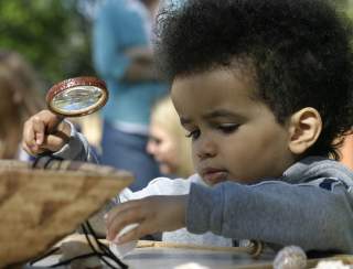 Child with a magnifying glass at the Roger Williams Park Zoo
