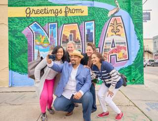 Sightseeing on Magazine Street in front of the Greetings from NOLA mural