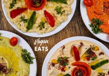 Multiple hummus platters with assorted vegetables