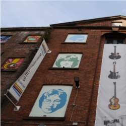 The exterior of the museum. An old brick warehouse building with paintings of the beatles in old windos