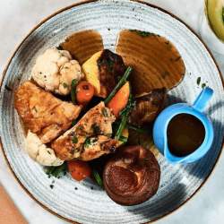A birds eye view of a plate with a roast dinner on including a jug of gravy. The dish is from Ma Boyle's