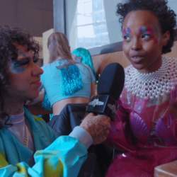 A person dressed in a blue outfit for the parade interviewing someone dressed in a shell outfit