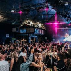 Inside a warehouse event with pink lasers and a crowd dancing