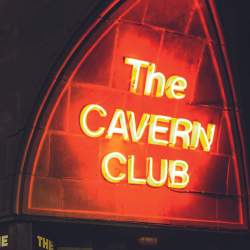 A neon red sign that reads 'Cavern Club' lit up at night time.