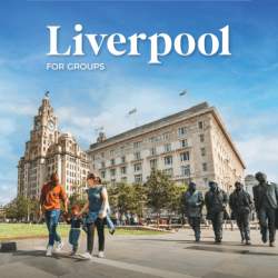 Image of Royal Liver Building and the Cunard building with The Beatles statue in front of them. To the left of the image is a family walking along the Pier Head.