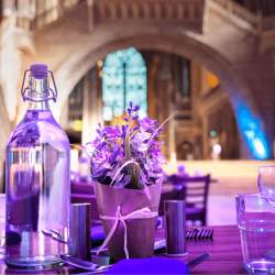 A close up of a table decorated with a lavender plant and bathed in purple light. The table is inside Liverpool's Anglican Cathedral