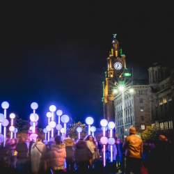 Red and white lampposts with people standing in-between them.