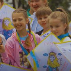 Children holding kites with colourful drawings on