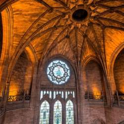 Inside the Liverpool Cathedral. A grand vaulted ceiling and stained glass windowas.