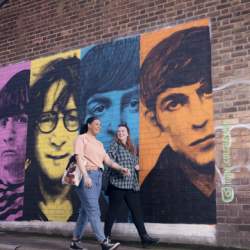 Two girls walk in front of the Beatles Street Art