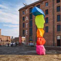 5 brightly coloured rocks, stacked on top of eachother outside Tate Liverpool