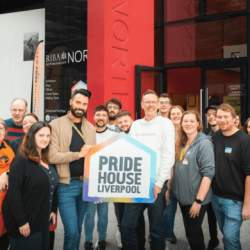 People standing outside Pride House holding the sign that reads Pride House Liverpool