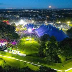 An evening festival scene with big top tents and crowds
