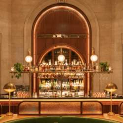 A portrait shot of an art deco interior bar with a large vaulted ceiling with red and green details.