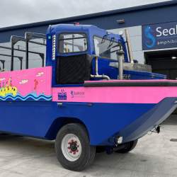 A blue and pink vehicle which drives and also goes in water.