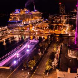The Liverpool Pier Head at night bathed in purple light with a cruise ship docked