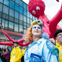 A giant octopus puppet looking over with funny googly eyes, a person in an underwater themed costume