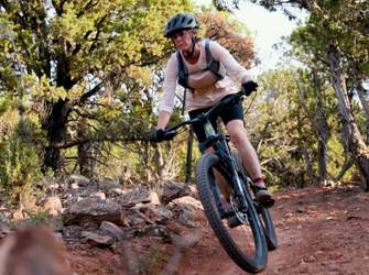 Mountain biker riding through wooded trail with rocky terrain and scenic landscape near Cedar City and Brian Head