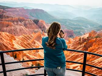Woman holding a camera at the Sunset Overlook in Cedar Breaks National Monument.