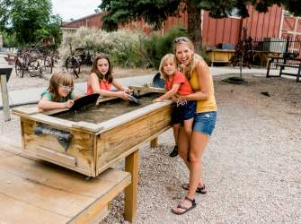A mom and three kids pan for gold outside at the Frontier Homestead State Park Museum in Cedar City, Utah.