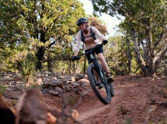 Mountain biker riding a red dirt trail through forest near Cedar City, Utah