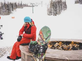 snowboarder sitting next to the fire at brian head resort