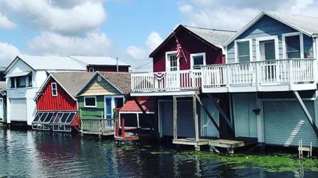 white, red, green and light blue boathouses on a lake