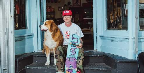 man sitting with a dog and a skateboard