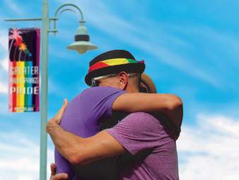 Couple hugging under GPS Pride flag