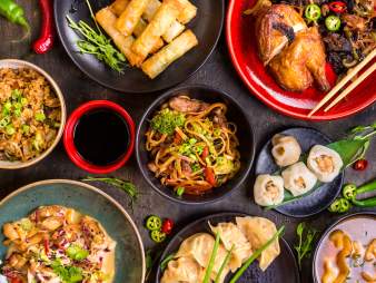 Spread of different Chinese food on black table.