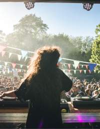 A performer on stage at the Trinity Garden Party Bristol with an audience in the background - credit Khali Ackford