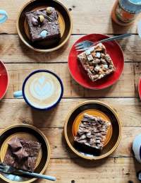 Various cakes and mugs of hot drinks on a table at Orchard Coffee Co in St George, East Bristol - credit Orchard Coffee Co