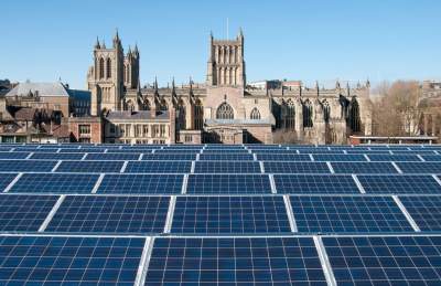 Solar panels on the roof of the We The Curious science centre on Millennium Square on Bristol's Harbourside, with Bristol Cathedral in the background - credit We The Curious