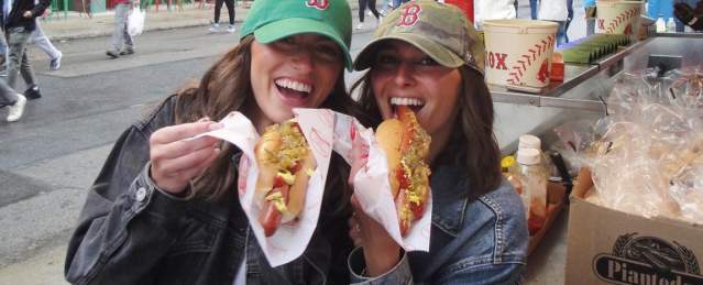 Two people eating Fenway Franks at a Red Sox Game