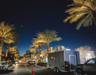 Food trucks lining the street at the Indio Food Park under the night sky.