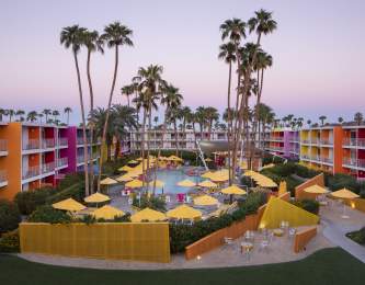 Aerial view of the pool at The Saguaro surrounded by the colorful resort buildings.